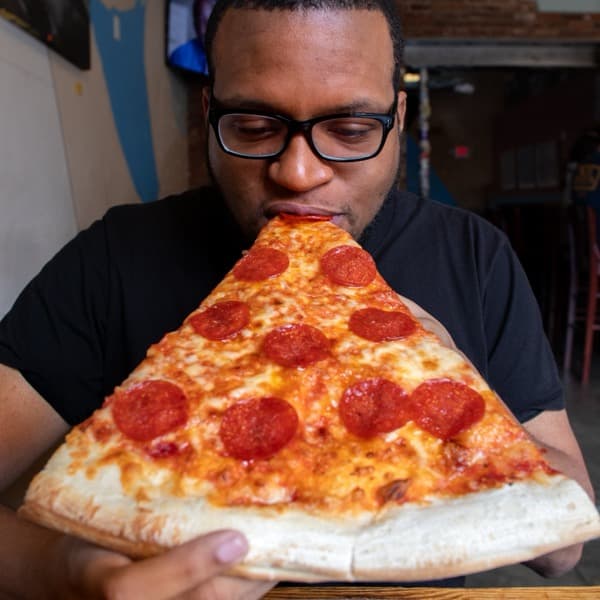 Cory Wilkins taking a bite of a giant pizza slice