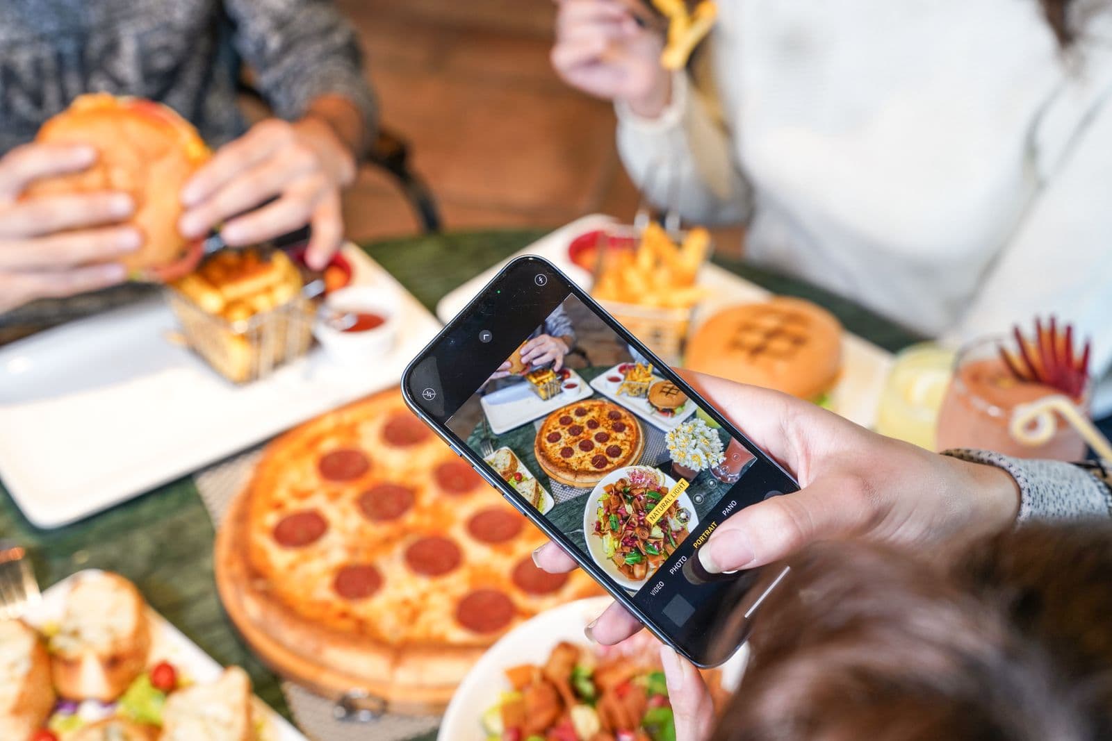 Friends laughing and sharing pizza together at a restaurant